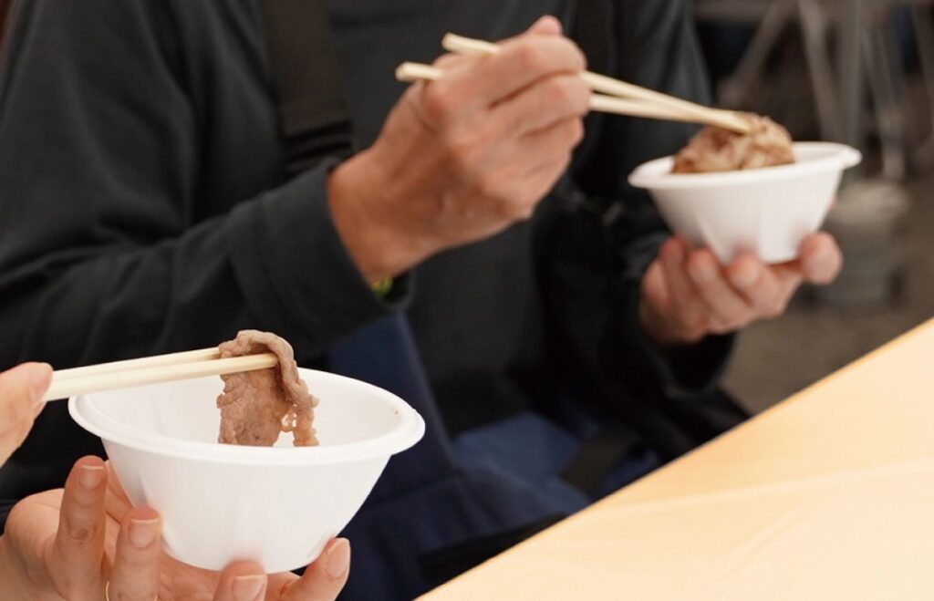 東京食肉市場まつりの無料試食で、しゃぶしゃぶを食べる来場者