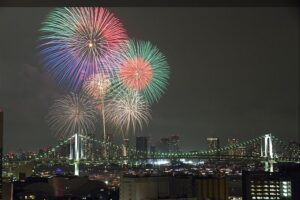 2015年8月8日の東京湾大華火祭。レインボーブリッジと湾岸の夜景の上に花火が開いている