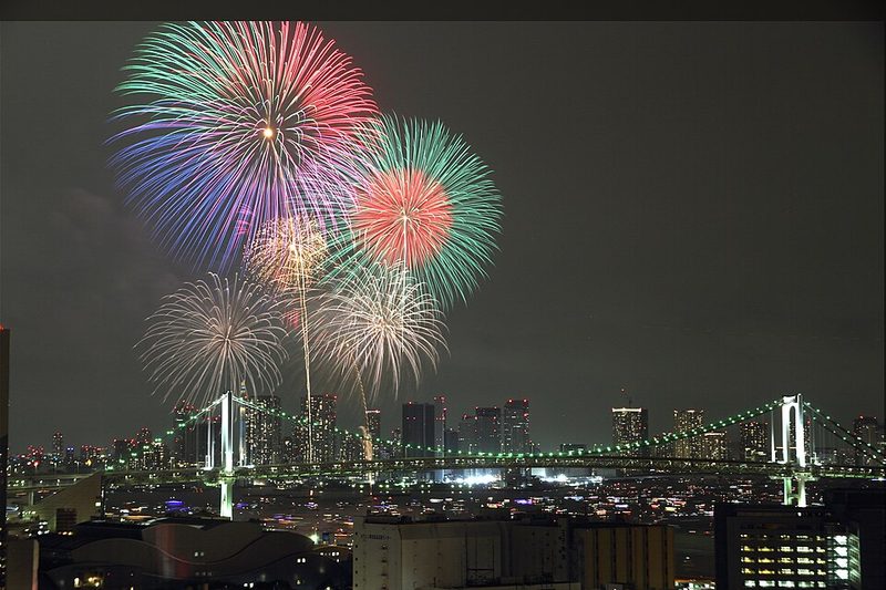 2015年8月8日の東京湾大華火祭。レインボーブリッジと湾岸の夜景の上に花火が開いている