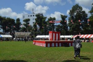 八街市のけやきの森公園。芝生広場に紅白幕のやぐらとテントが並び、周囲をケヤキなどの高木が囲む