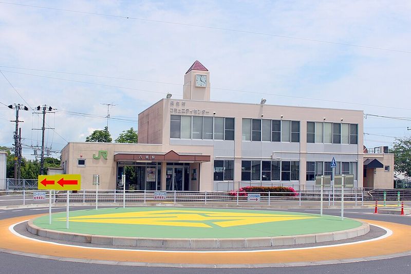 JR外房線八積駅の駅舎とロータリー。時計塔のある2階建ての建物に長生村コミュニティセンターが入っている