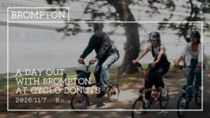 木陰の道を折りたたみ自転車Bromptonで走る3人の写真に、BROMPTONのロゴと「A DAY OUT WITH BROMPTON AT CYCLO DONUTS 2026/11/7(土)-8(日)」の文字を重ねた告知画像