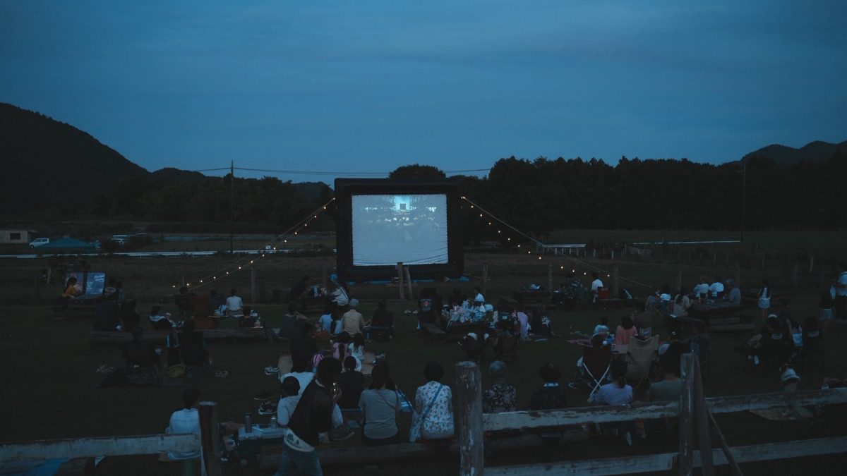 夕暮れの服部牧場の放牧地でスクリーンの映画を観る来場者