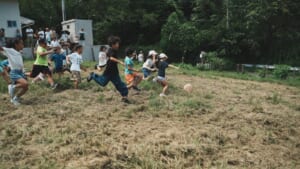 服部牧場の斜面を転がるチーズを子どもたちが走って追いかける様子