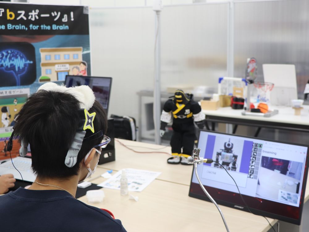 2025年の一般公開の「脳動ロボットの国」。頭に脳波計を着けた子どもが、画面と小型ロボットの前で操作に挑戦している