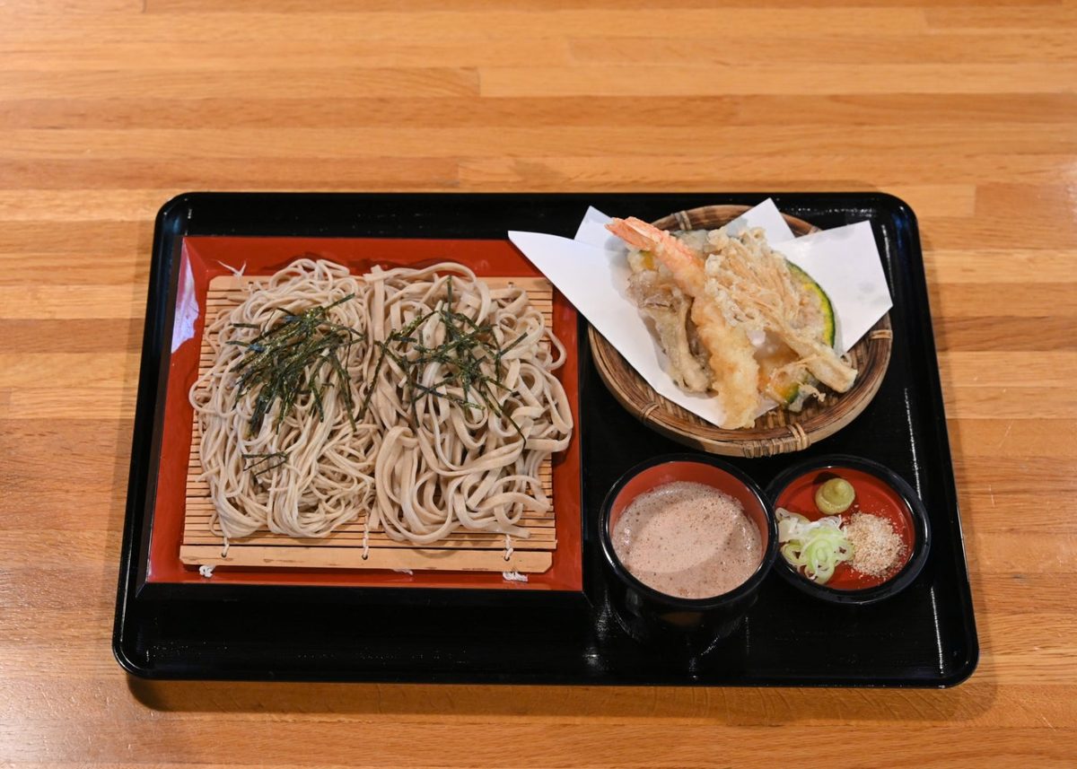 黒い盆に、海苔をかけたざるそば、エビなどの天ぷら、つゆ、薬味