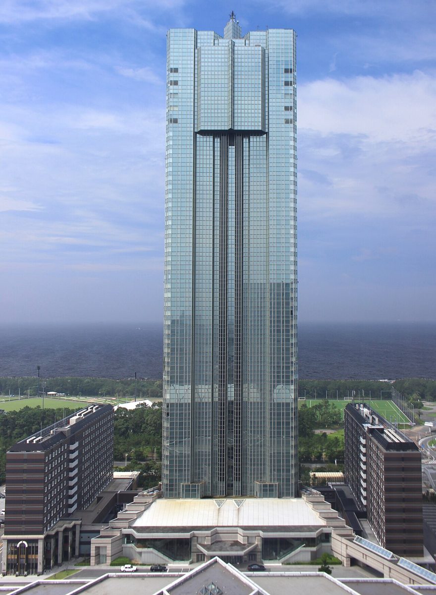 海を背に建つガラス張りの高層ホテル、アパホテル&リゾート〈東京ベイ幕張〉のタワー棟と左右の低層棟