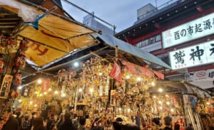 夜の鷲神社の酉の市。熊手がぎっしり飾られた店が並び人が集まっている