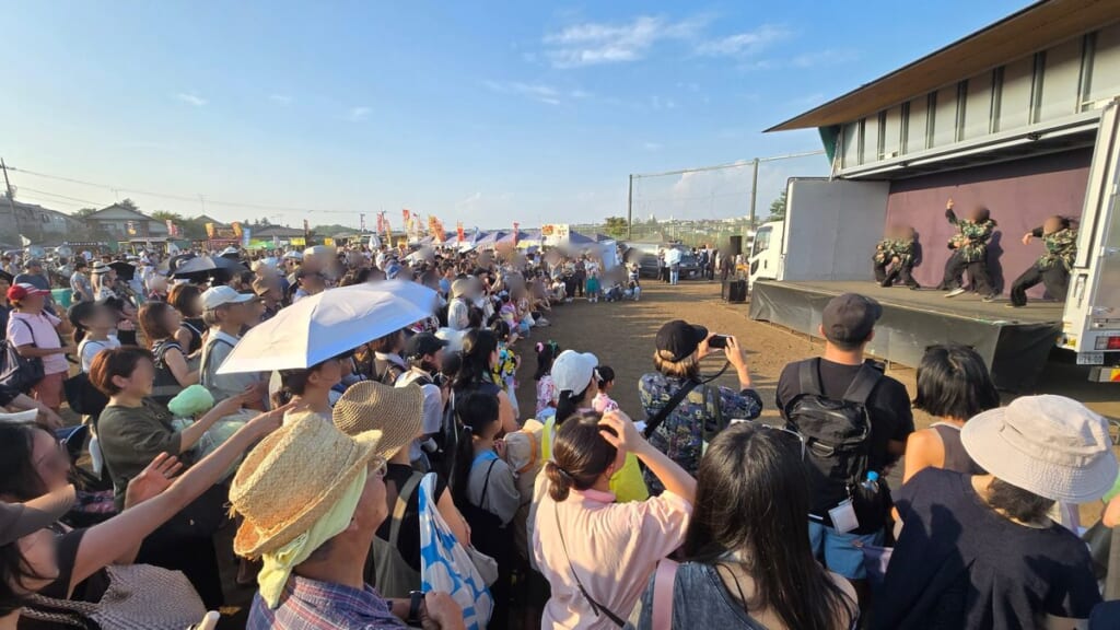 あざみ野まつりのトラックステージ前に集まる観客と模擬店のテント