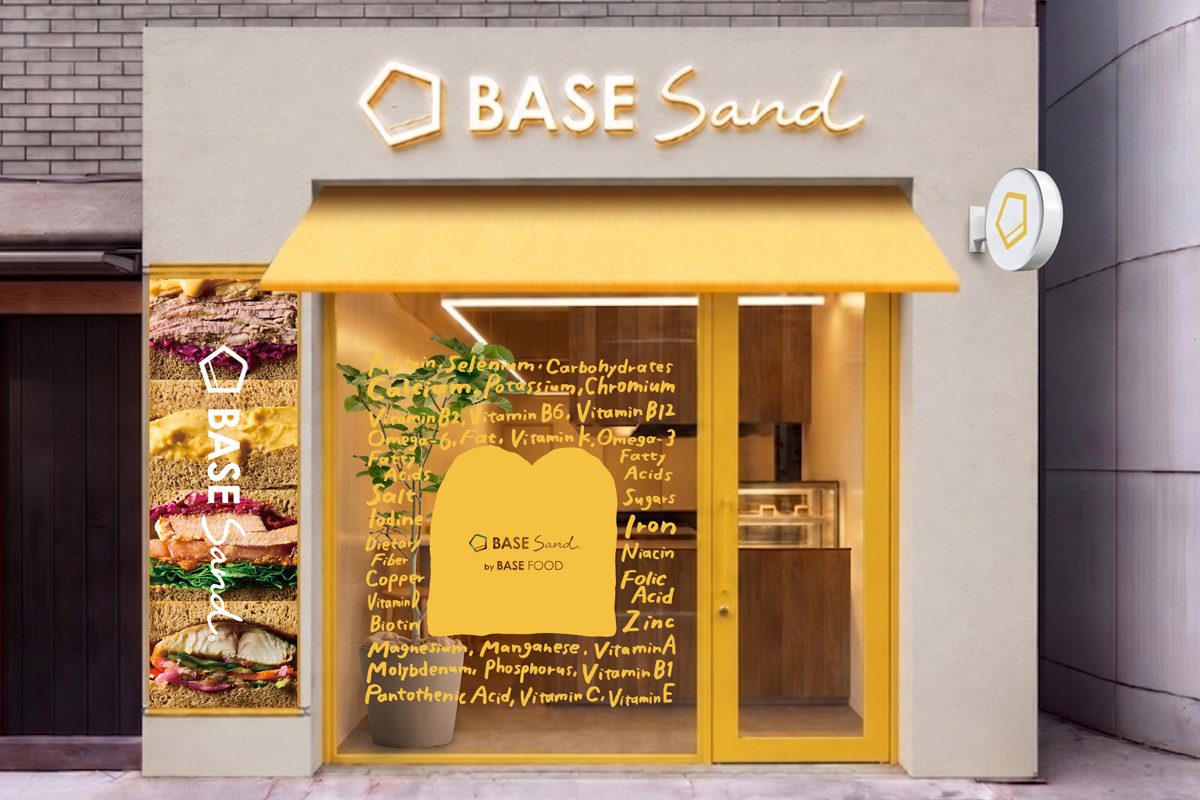 黄色いひさしと「BASE Sand」の看板、サンドイッチの写真を貼った窓がある店の外観のイメージ図