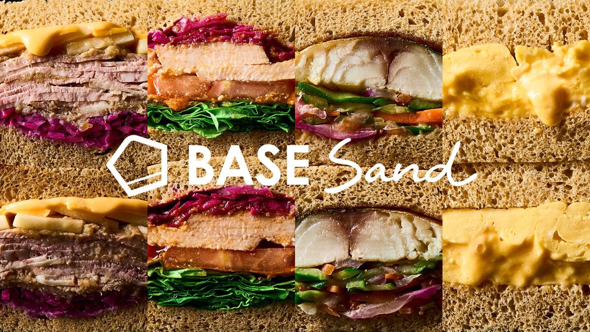 全粒粉パンにチキンや紫キャベツ、サバ、卵などを挟んだサンドの断面を並べ、中央にBASE Sandのロゴを置いた写真
