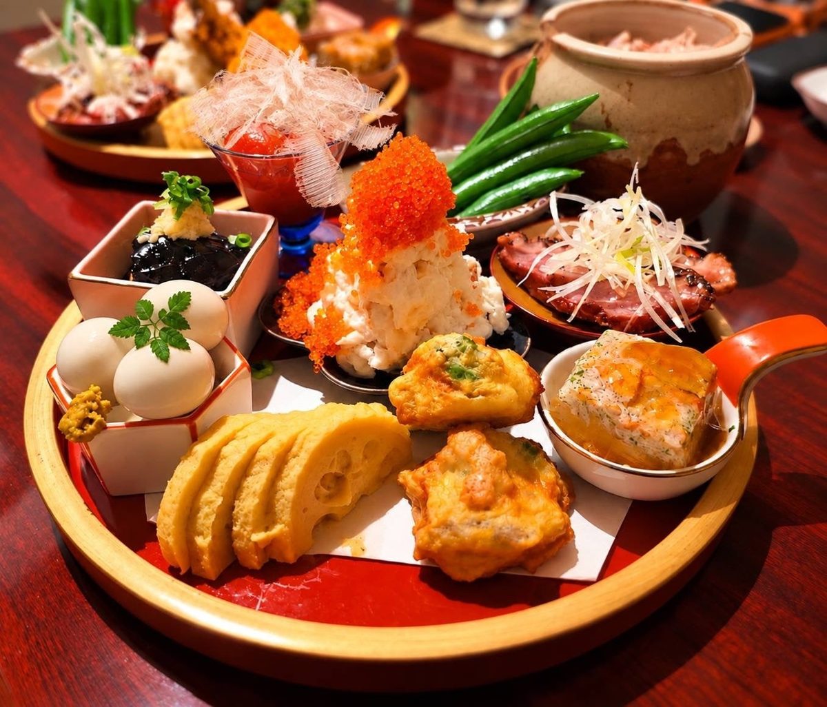 丸い盆に、ポテトサラダやうずら卵、さつま揚げ、スナップエンドウなどの小鉢を盛り合わせた八寸の写真