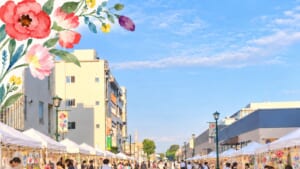 BLOOM MARCHE公式サイトのメインビジュアル。青空の下、街灯と花のバナーが並ぶ駅前の通りに白いテントのブースが続き、左上に水彩の花のイラスト