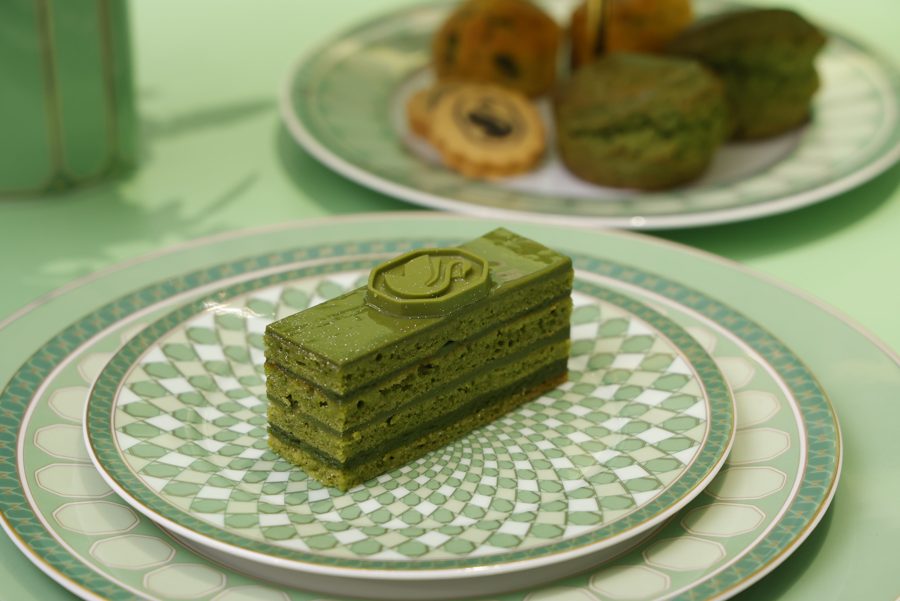 緑と白の幾何学模様の皿にのった抹茶のオペラ。奥に焼き菓子の皿