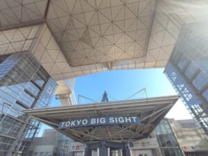 東京ビッグサイトの逆三角形の会議棟を真下の入口付近から見上げた写真。手前に「TOKYO BIG SIGHT」の看板