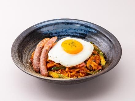 ナポリタンの上に目玉焼きと2本のソーセージをのせた器の写真