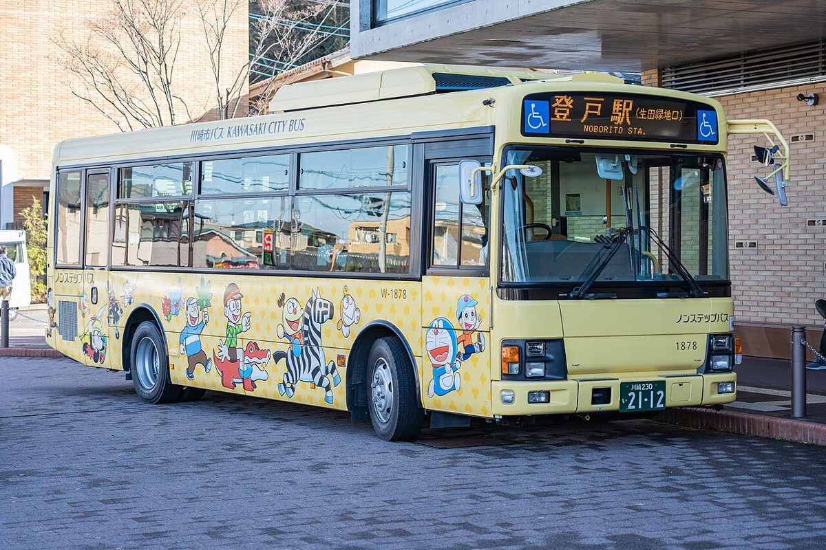 ドラえもんなどのキャラクターが描かれた黄色い車体に「登戸駅」と表示されたバス