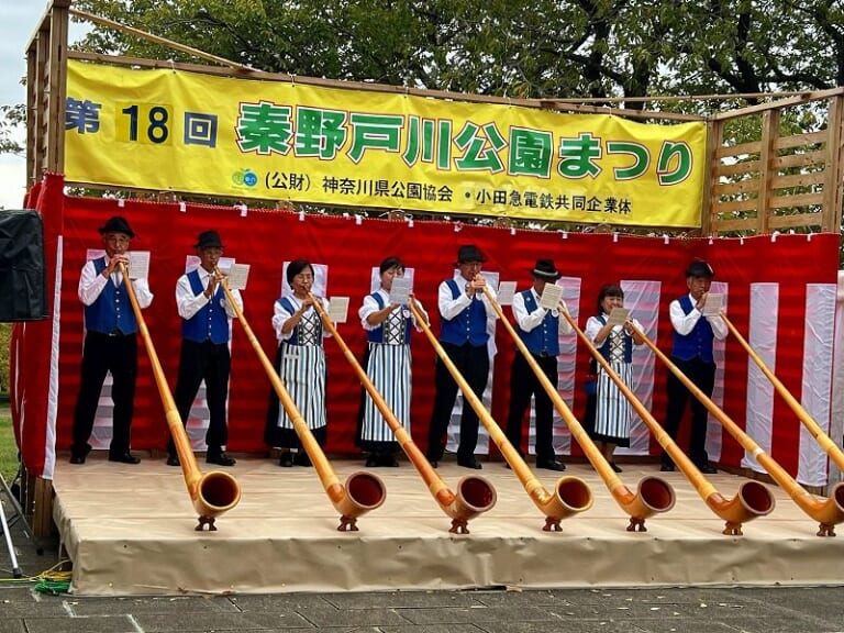 第18回秦野戸川公園まつりのステージでアルプホルンを演奏する奏者たち