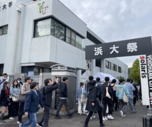 「浜大祭」と書かれた黒いゲートをくぐって、来場者がキャンパスに入っていく様子