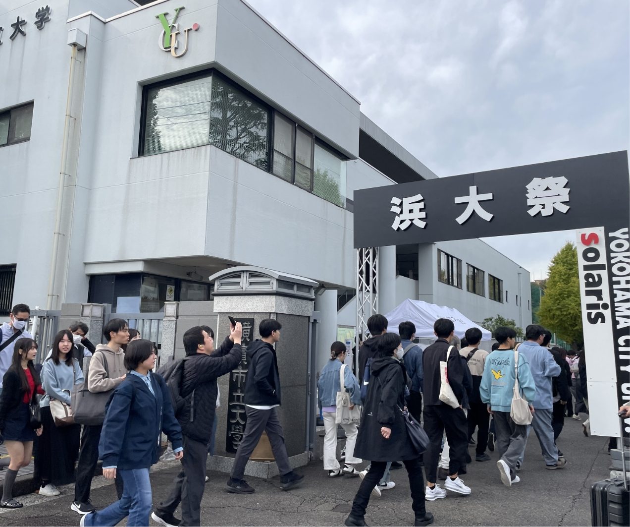 「浜大祭」と書かれた黒いゲートをくぐって、来場者がキャンパスに入っていく様子