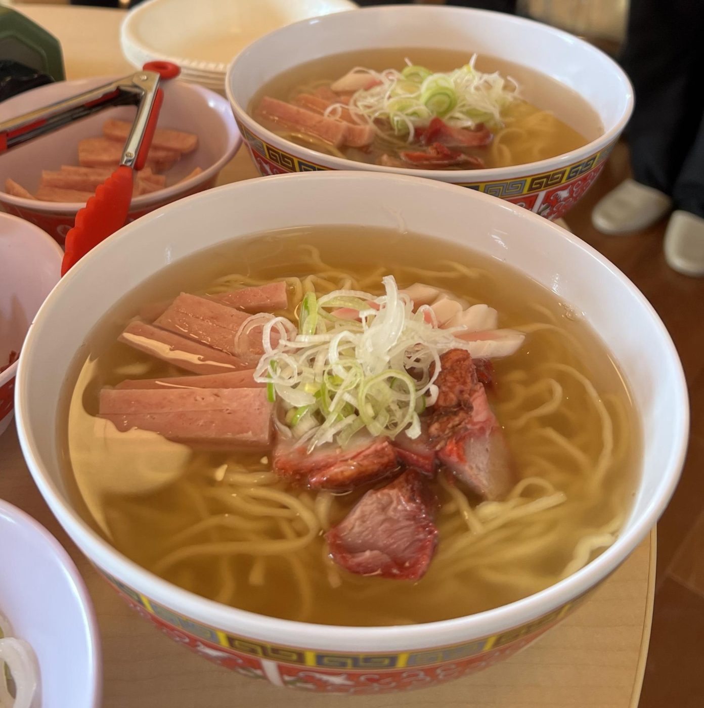 どんぶりに入ったサイミン。透き通ったスープの麺の上にスパム、チャーシュー、刻みねぎ