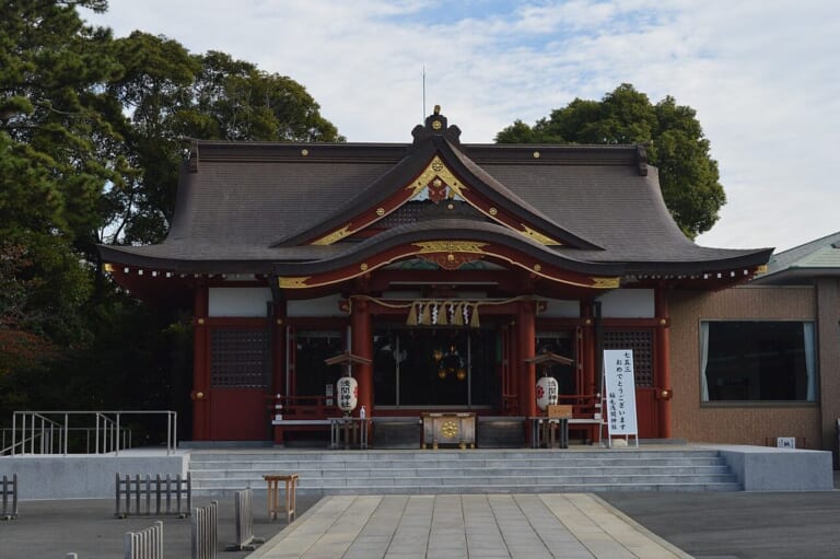稲毛浅間神社の社殿。朱塗りの柱と黒い屋根の拝殿の前に石段と広い前庭がある