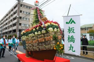 野菜をかごに積み上げ、JAの旗と「板橋丸」の旗を立てた宝船の山車を、はっぴ姿の人たちが綱で引いている