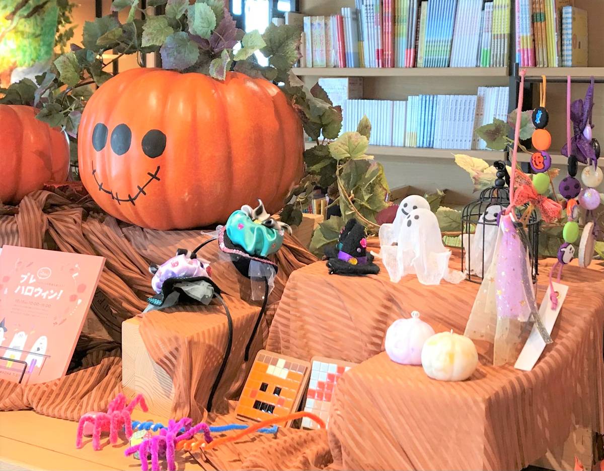 本棚の前に大きなカボチャのオブジェやおばけの飾りが並ぶハロウィンの装飾