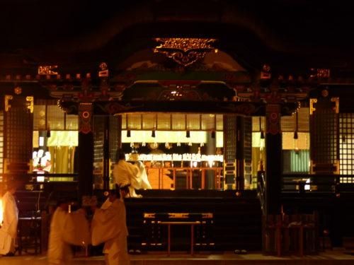 夜、灯りのともった香取神宮の拝殿の中で、白い装束の神職が祭典に奉仕している