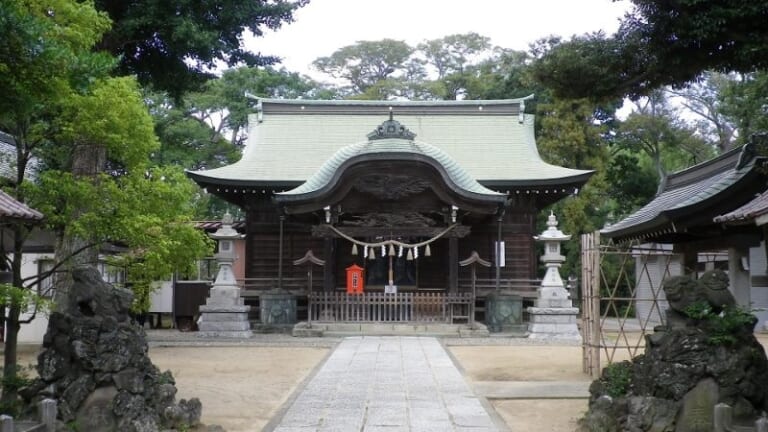 菊田神社の拝殿。石畳の参道の先に銅板葺きの屋根の社殿があり、手前左右に岩山の狛犬が立つ