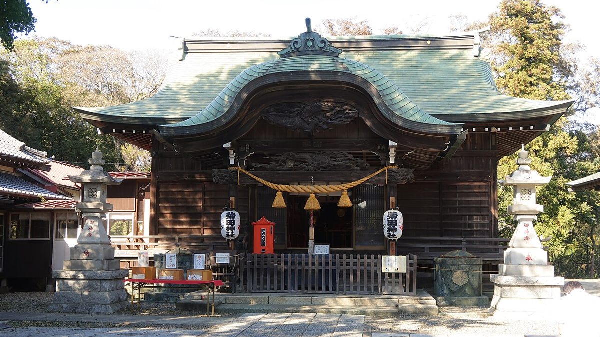 菊田神社の拝殿。緑青色の唐破風屋根の下に「菊田神社」の提灯が2つ下がり、左右に石灯籠が立つ