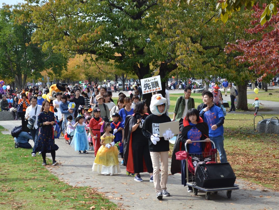 公園の園路を仮装した子どもと保護者が列になって歩く、過去のきたまちハロウィン仮装キッズパレード