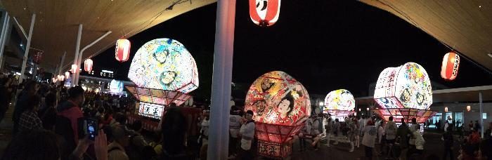 夜の北本駅西口に並ぶ明かりのともったねぷたと見物客
