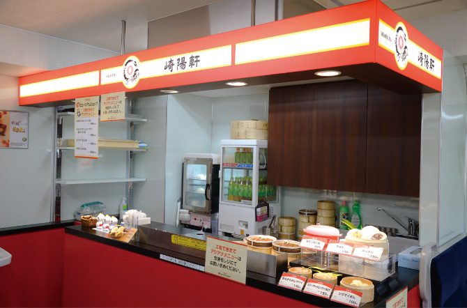 赤い看板に「崎陽軒」の文字があるカウンターと、蒸し器や商品が並ぶ棚