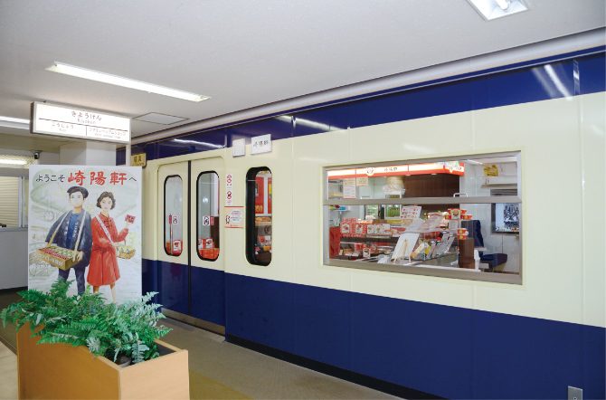 青と白の電車の車体を模した壁と窓、入口の横に崎陽軒の昔のポスター