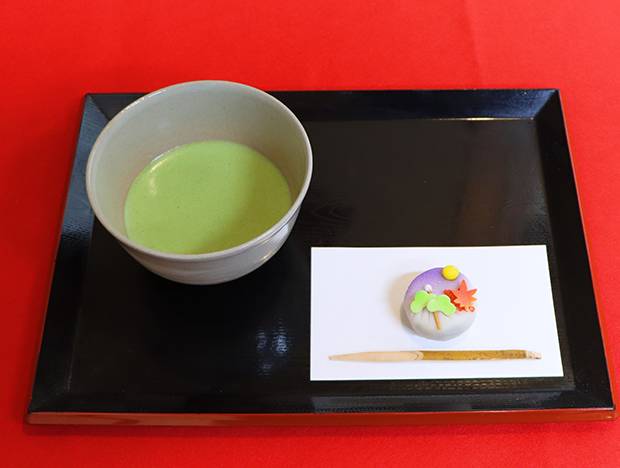 黒い盆にのった抹茶と、紫の地に紅葉と松をあしらった練り切り