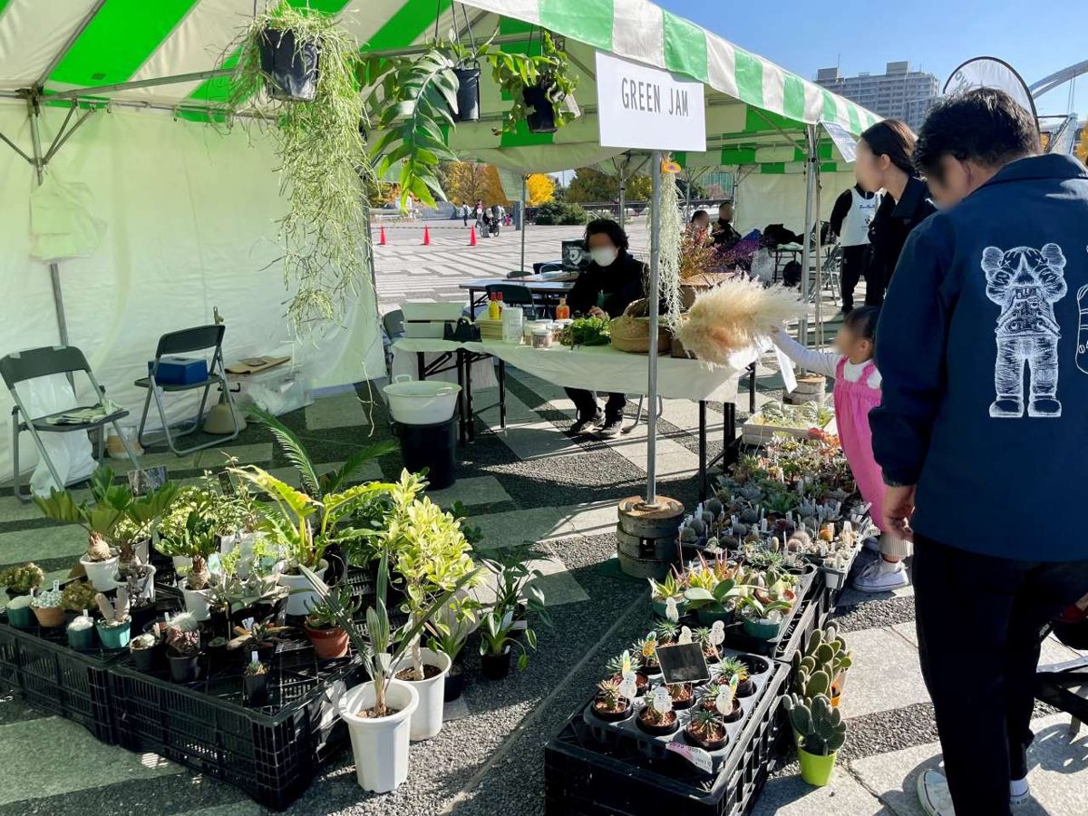 緑と白のテントの下に観葉植物や多肉植物の鉢が並び、来場者が見ている出展ブース