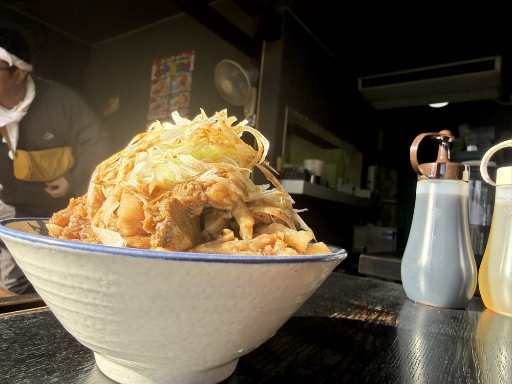 白い丼にヤサイともやし、厚切りのチャーシューがのった化学飯能店のラーメン