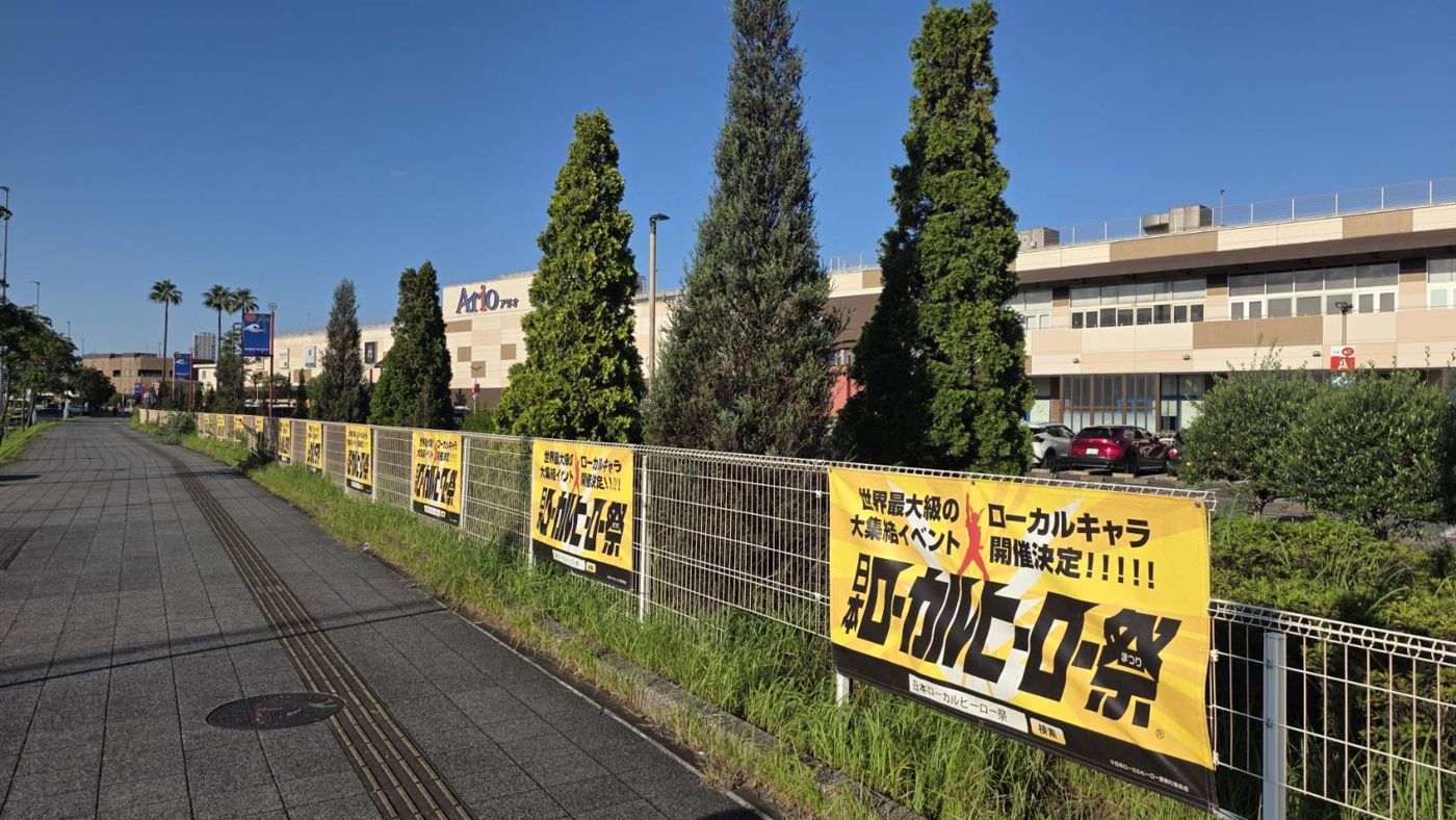 アリオ蘇我の前の歩道沿いのフェンスに、黄色い「日本ローカルヒーロー祭」の横断幕が並んでいる