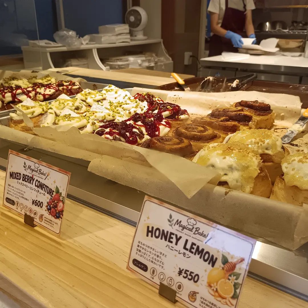 ショーケースに、ベリーソースやピスタチオをのせたシナモンロールと、ハニーレモンのロールが並び、「HONEY LEMON ¥550」「MIXED BERRY CONFITURE ¥600」の札が立っている