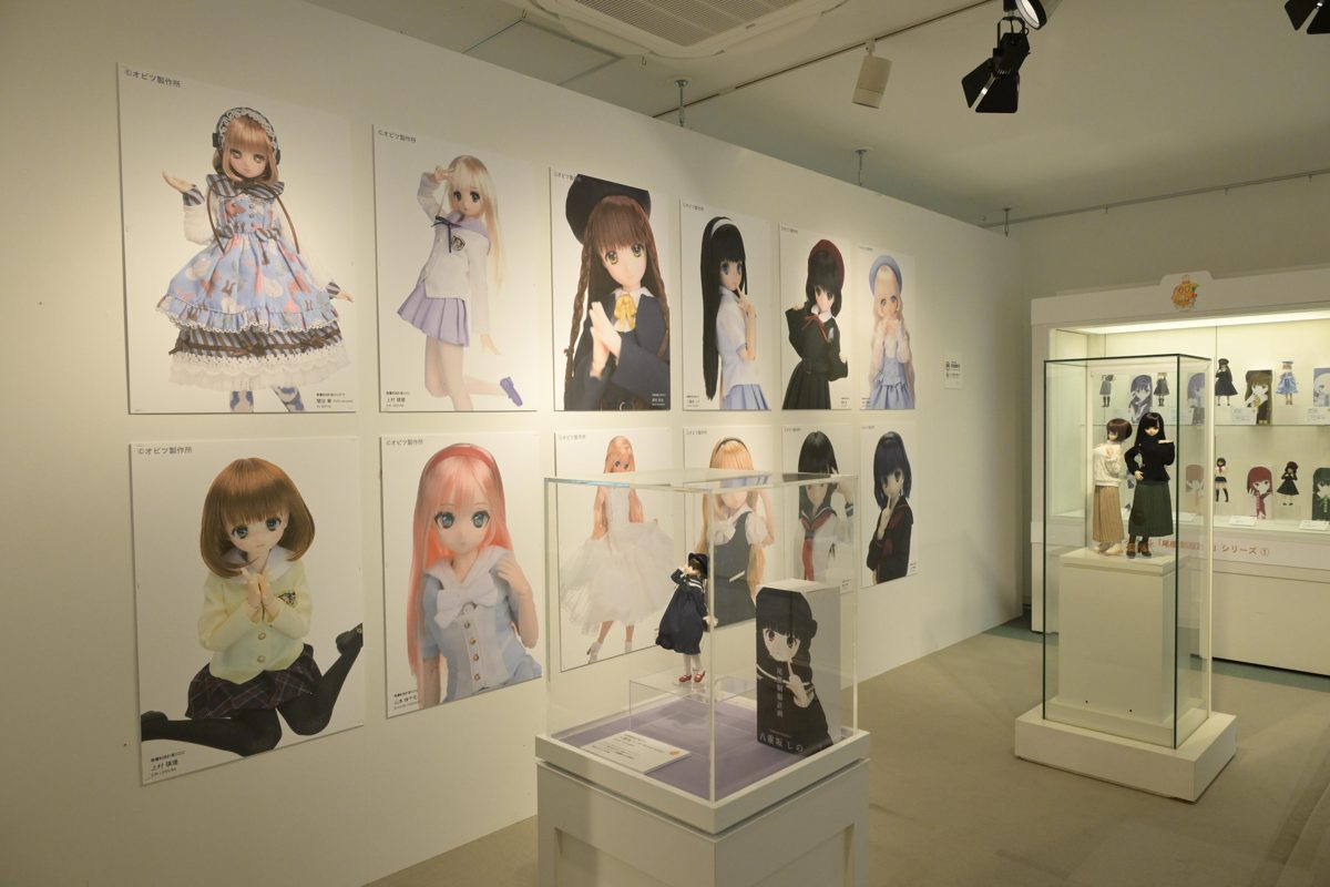 壁にオビツドールのポスターが並び、ガラスケースにドールや洋服が展示された白い展示室