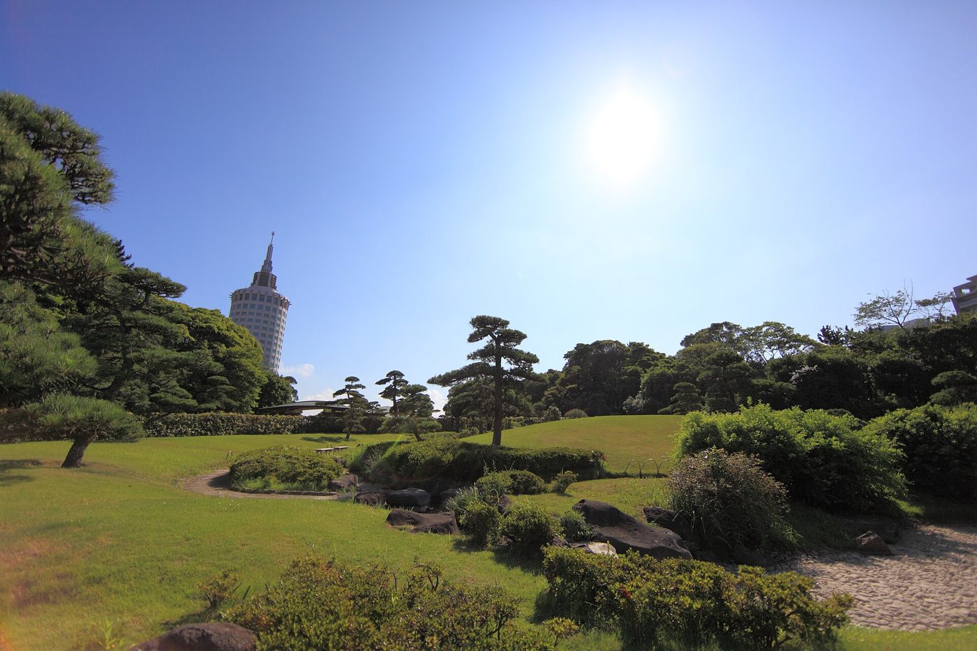 見浜園の芝生の築山と松の木、奥にホテルのタワー