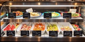 ガラスのショーケースに、名札を付けた小皿料理のバットが2段に並んでいるイメージ
