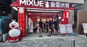 MIXUE 横浜中華街店の店頭。赤い看板と雪だるまのキャラクター「雪王」の像、店の前に並ぶ客