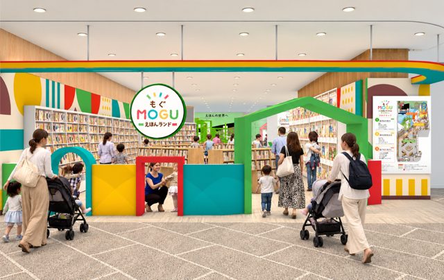 緑とオレンジのアーチと「MOGU えほんランド」の丸い看板の入口、奥に絵本の棚が並び、ベビーカーの親子が行き交う店頭のイメージ図