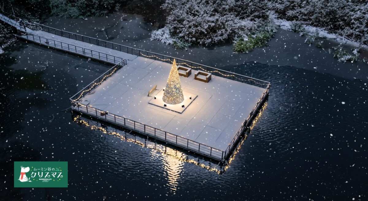 夜の湖の上に張り出したテラスの中央に光るツリーが立ち、雪が舞っているように見える上空からの写真