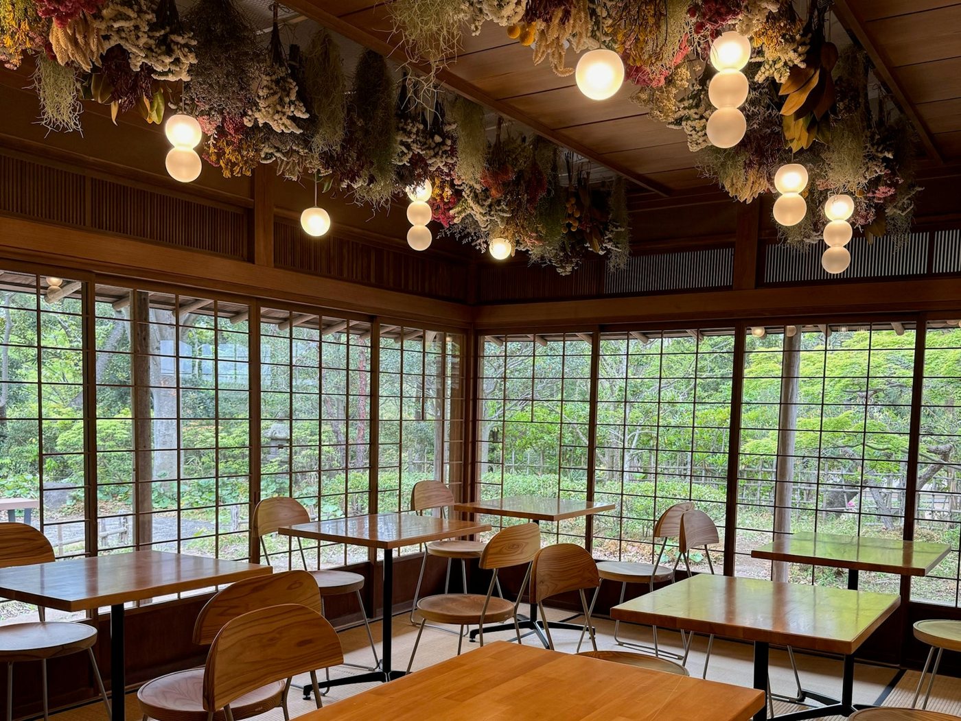 木の格子窓に面したテーブルと天井のドライフラワーがあるカフェ棟