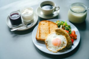 Morning Park Cafeの開店告知に掲載されたトースト、目玉焼き、ソーセージ、サラダのプレートと飲み物