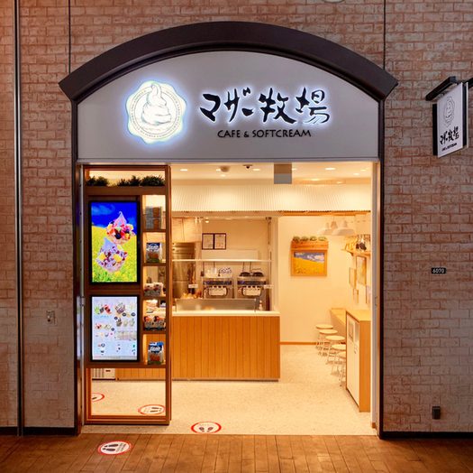 れんが調の壁に「マザー牧場 CAFE & SOFTCREAM」の看板が掛かった店の入口