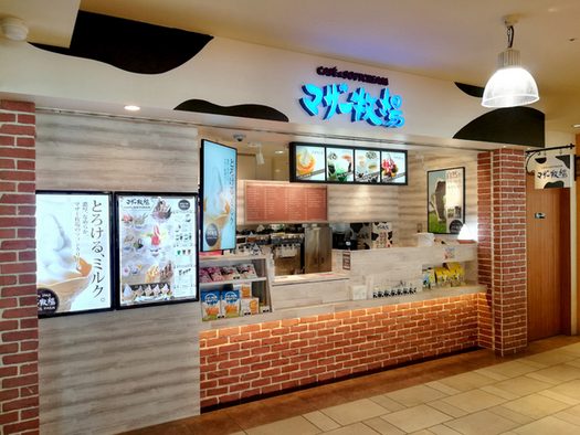 レンガ調のカウンターの上に牛柄の看板とメニューの画面がある店頭